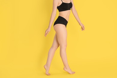 Photo of Woman with slim body posing on yellow background, closeup