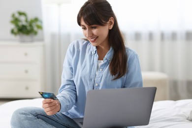 Online banking. Smiling woman with credit card and laptop paying purchase at home