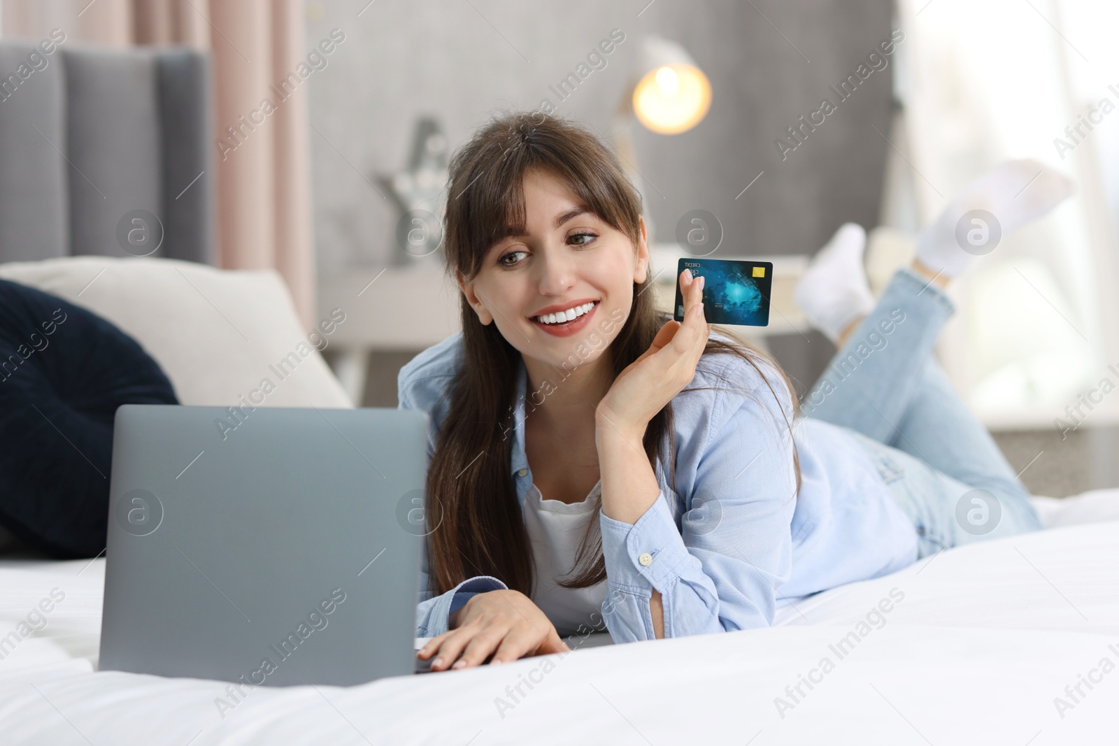 Photo of Online banking. Smiling woman with credit card and laptop paying purchase at home