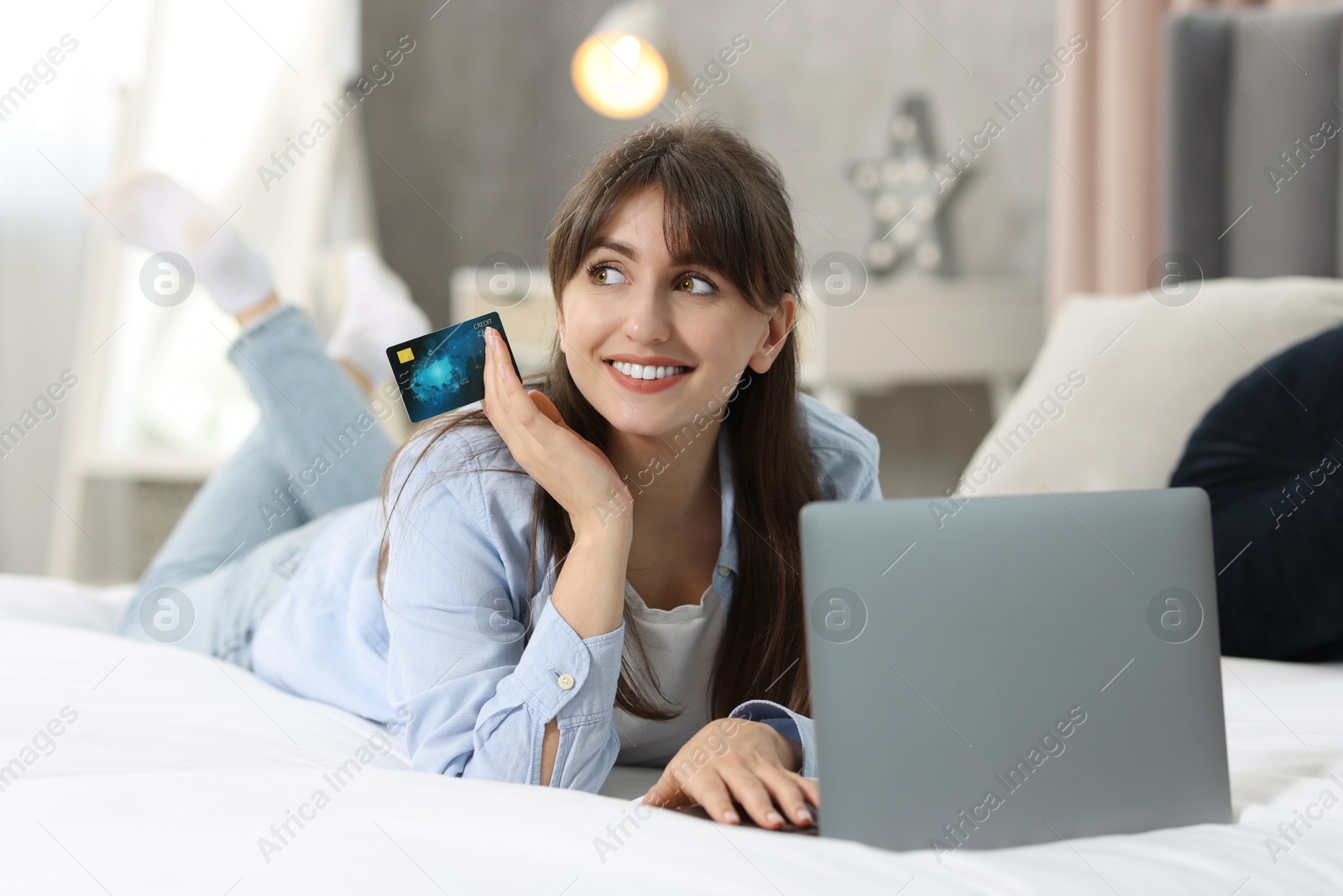 Photo of Online banking. Smiling woman with credit card and laptop paying purchase at home