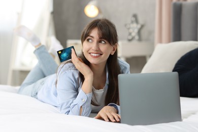 Online banking. Smiling woman with credit card and laptop paying purchase at home