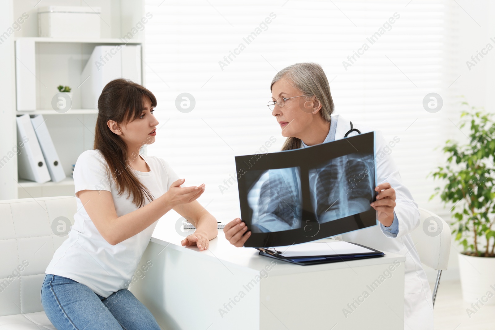 Photo of Lung disease. Doctor showing chest x-ray to her patient in clinic