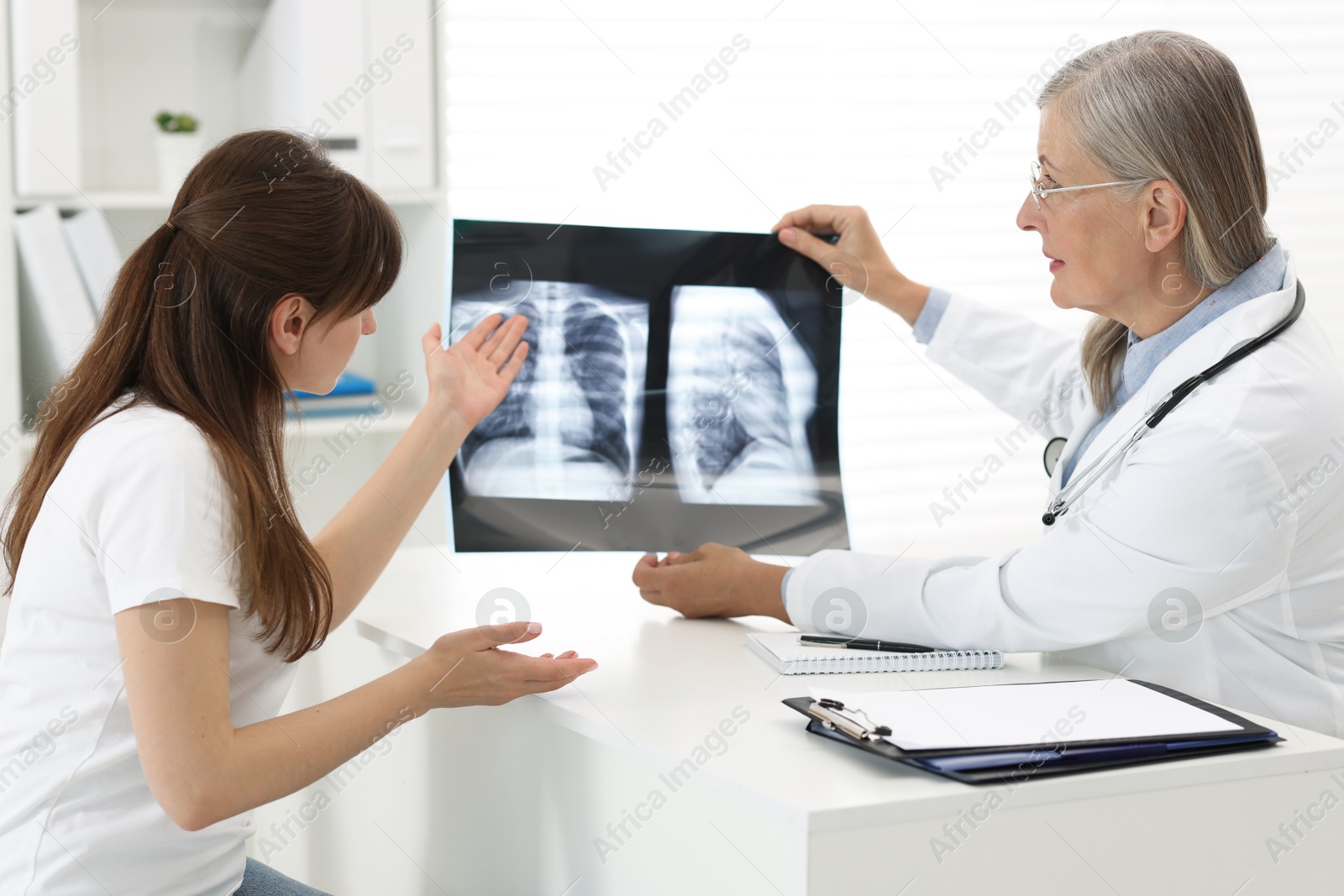 Photo of Lung disease. Doctor showing chest x-ray to her patient in clinic