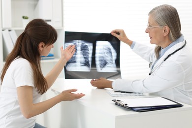 Photo of Lung disease. Doctor showing chest x-ray to her patient in clinic