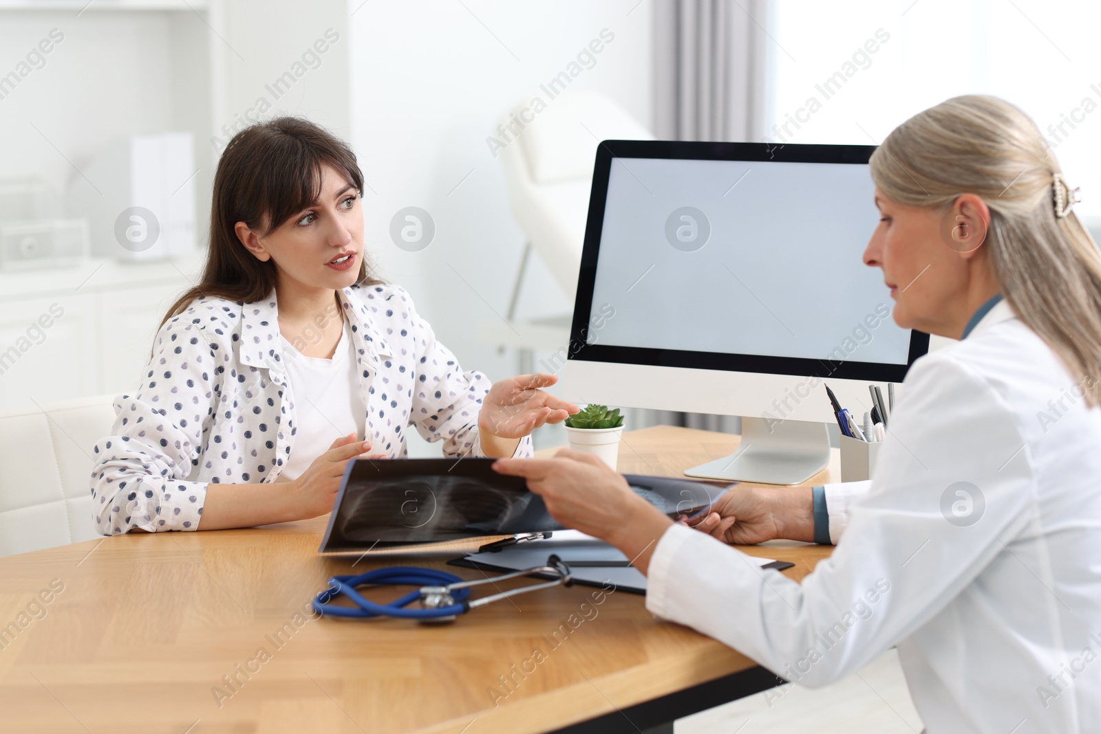 Photo of Lung disease. Doctor showing chest x-ray to her patient in clinic