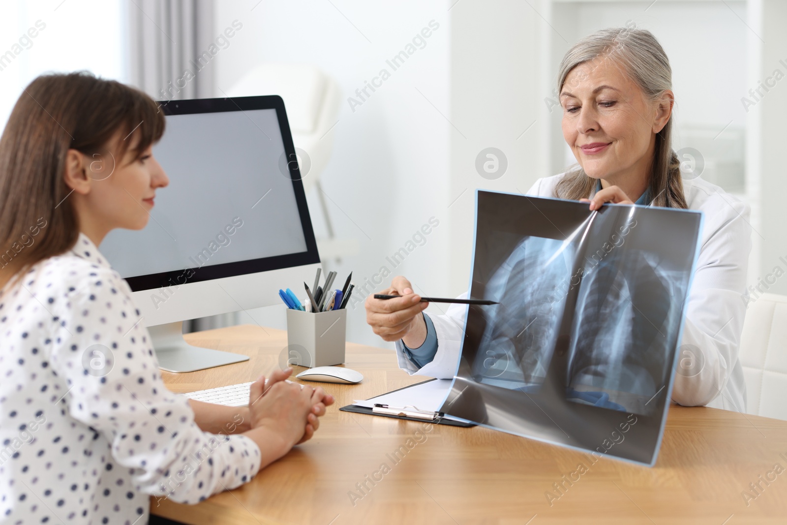 Photo of Lung disease. Doctor showing chest x-ray to her patient in clinic