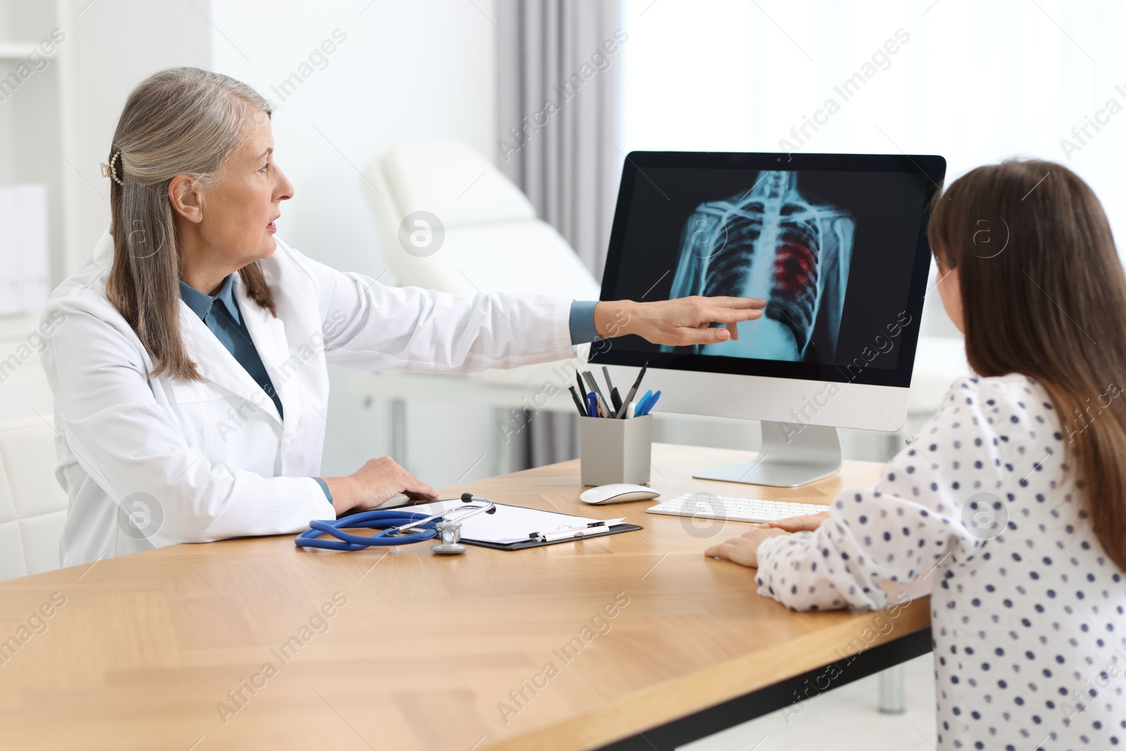 Photo of Lung cancer. Doctor showing chest x-ray to her patient in clinic