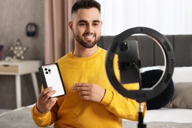 Photo of Technology blogger reviewing phone and recording video with smartphone and ring lamp at home