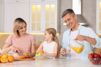 Photo of Happy family making juice at white marble table in kitchen