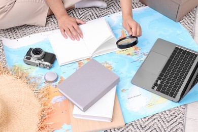Photo of Travel blogger with magnifying glass and map planning trip, closeup
