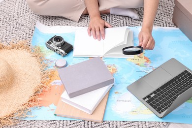 Travel blogger with magnifying glass and map planning trip, closeup