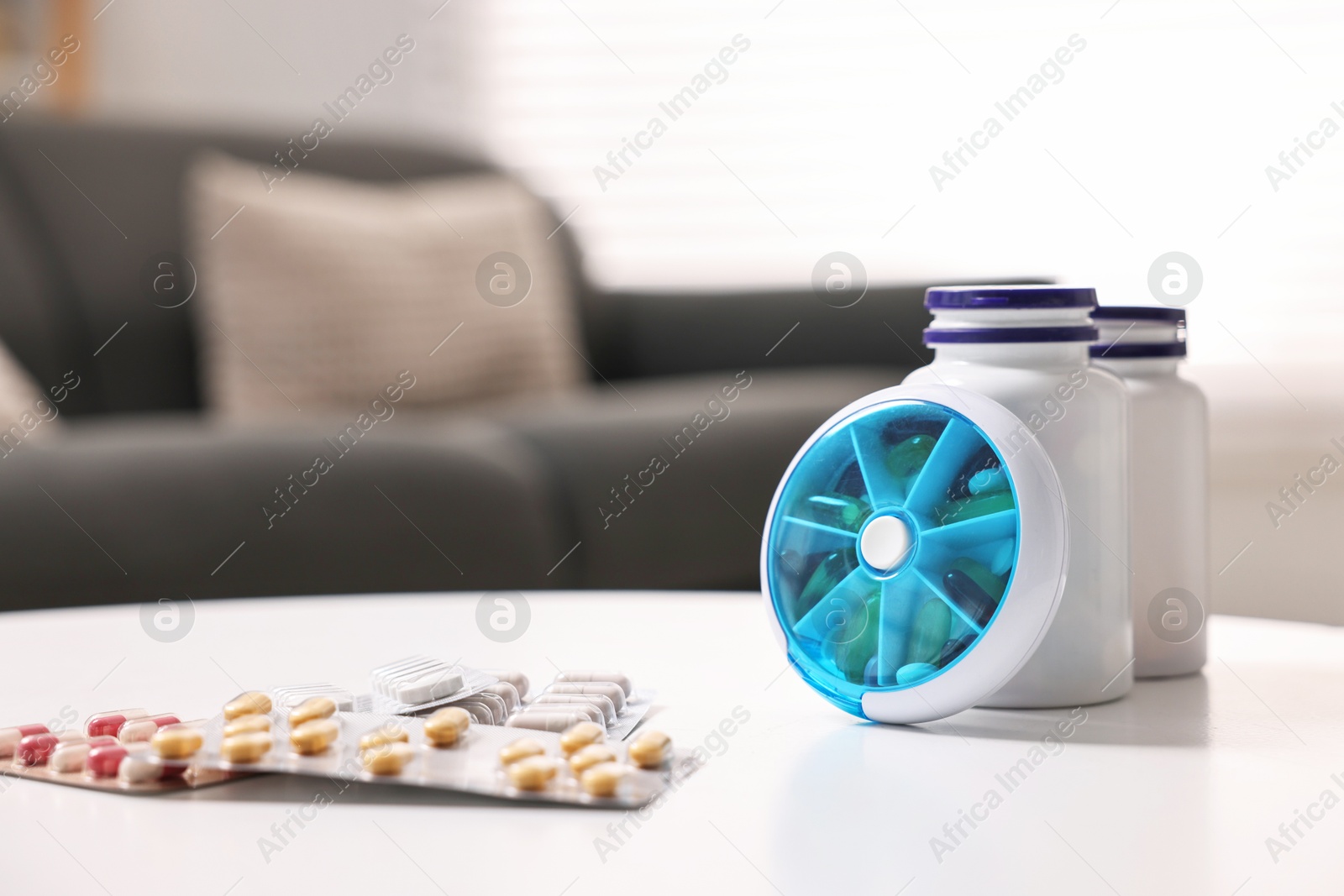 Photo of Different pills, organizer and medical jars at white table, closeup. Space for text