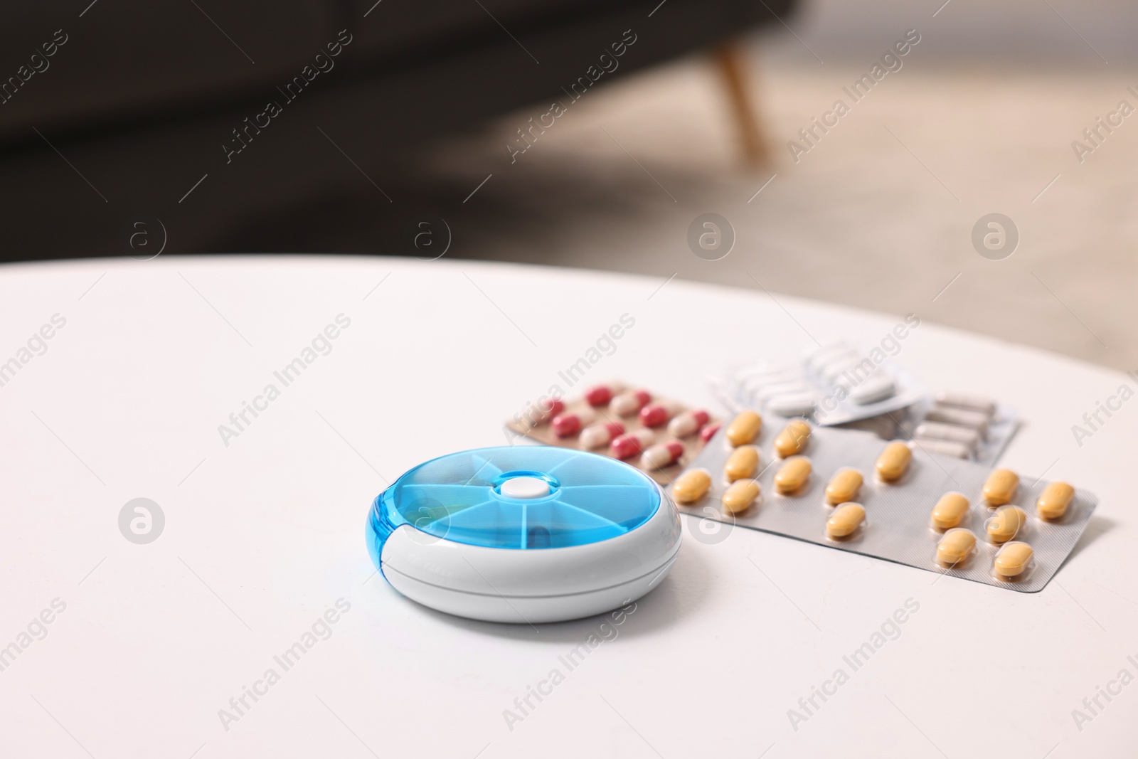 Photo of Different pills and organizer at white table, closeup. Space for text