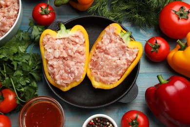 Photo of Raw stuffed peppers with ground meat and ingredients on light blue wooden table, flat lay