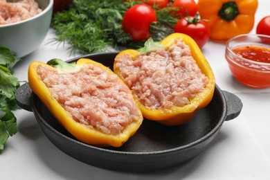 Photo of Raw stuffed peppers with ground meat and ingredients on white tiled table