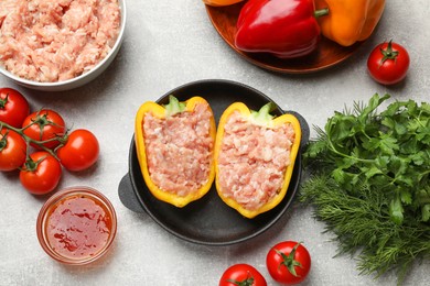 Photo of Raw stuffed peppers with ground meat and ingredients on light grey table, flat lay