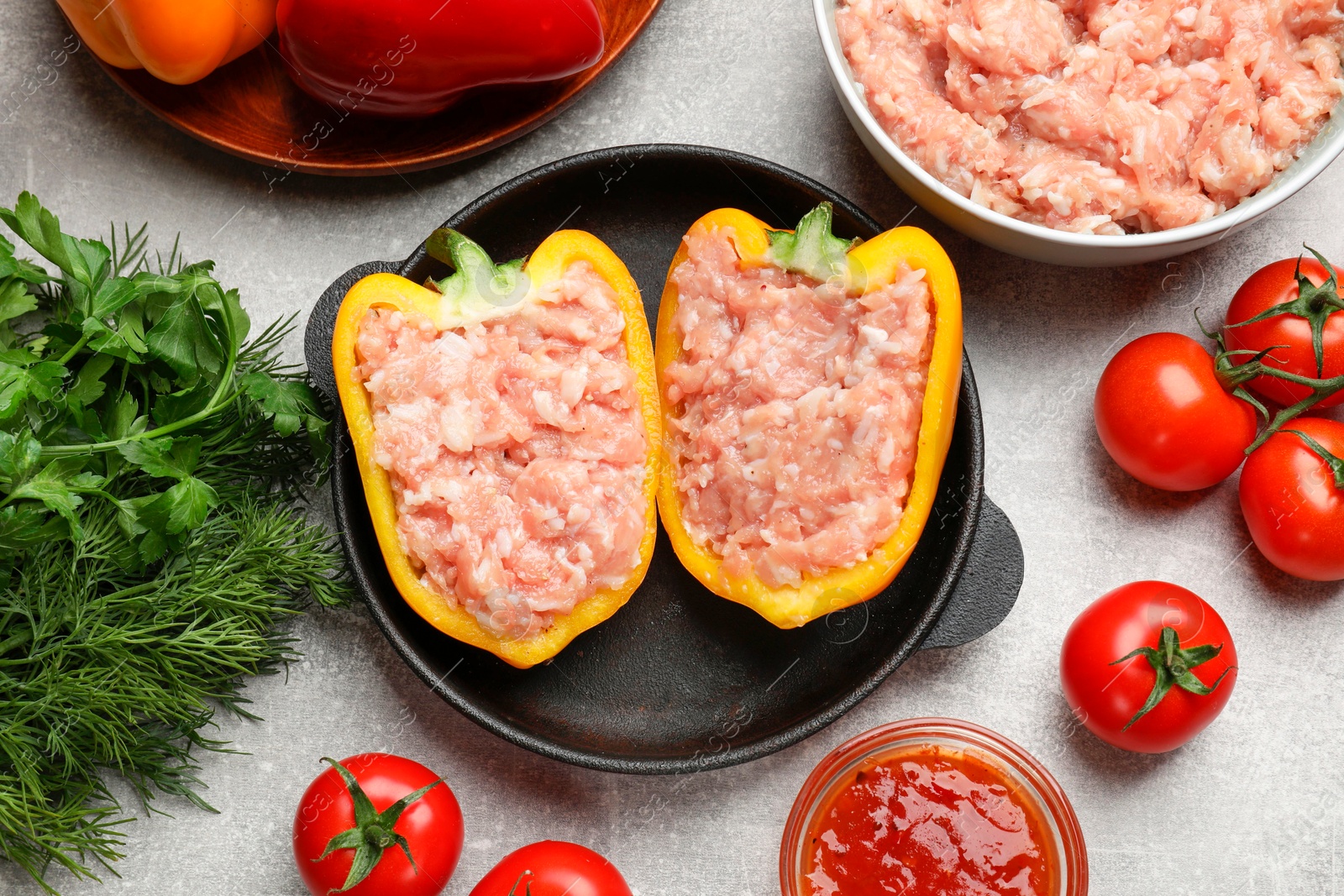 Photo of Raw stuffed peppers with ground meat and ingredients on light grey table, flat lay
