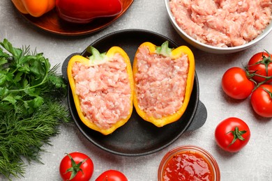 Raw stuffed peppers with ground meat and ingredients on light grey table, flat lay