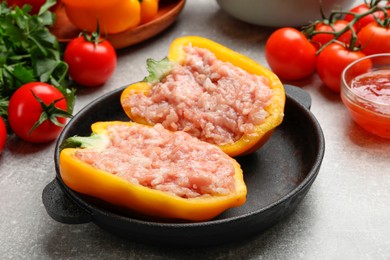 Raw stuffed peppers with ground meat and ingredients on light grey table