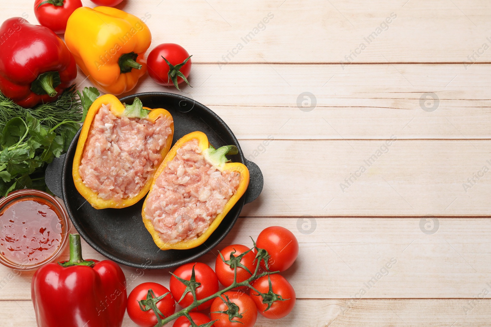 Photo of Raw stuffed peppers with ground meat and ingredients on light wooden table, flat lay. Space for text