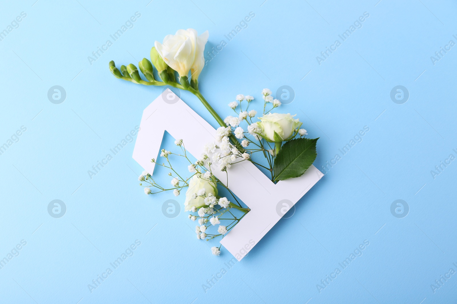 Photo of Paper number 1 and beautiful flowers on light blue background, top view