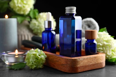 Photo of Spa composition. Cosmetic products, burning candles and hydrangea flowers on gray table, closeup