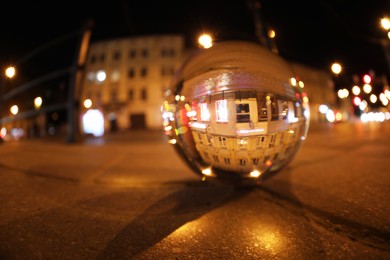 Beautiful city street, overturned reflection. Crystal ball on asphalt road at night. Wide-angle lens