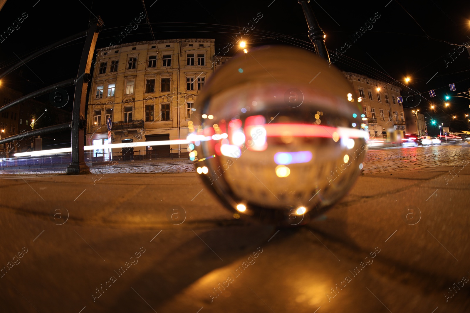 Photo of Crystal ball on asphalt road at night, selective focus. Wide-angle lens