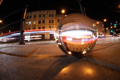 Crystal ball on asphalt road at night, selective focus. Wide-angle lens