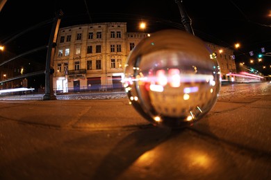 Photo of Crystal ball on asphalt road at night, selective focus. Wide-angle lens