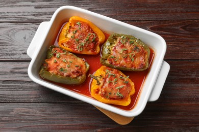 Photo of Tasty stuffed peppers in dish on wooden table, top view