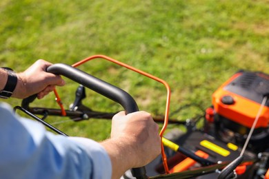 Man cutting grass with lawn mower outdoors, closeup