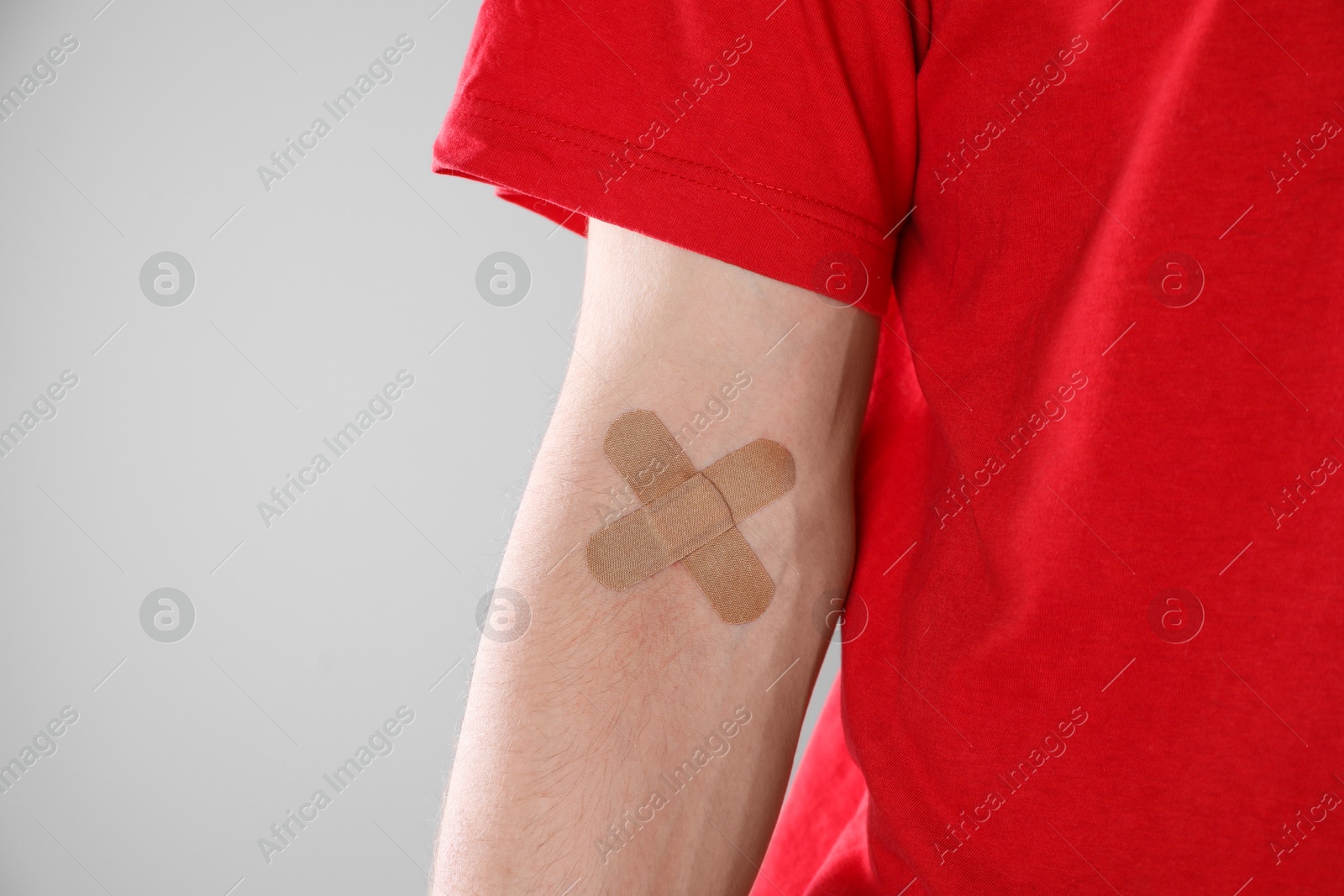 Photo of Blood donation. Woman with sticking plaster on her arm against gray background, closeup. Space for text