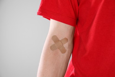 Photo of Blood donation. Woman with sticking plaster on her arm against gray background, closeup. Space for text