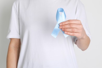 Photo of International Psoriasis Day. Woman with light blue ribbon as symbol of support on white background, closeup