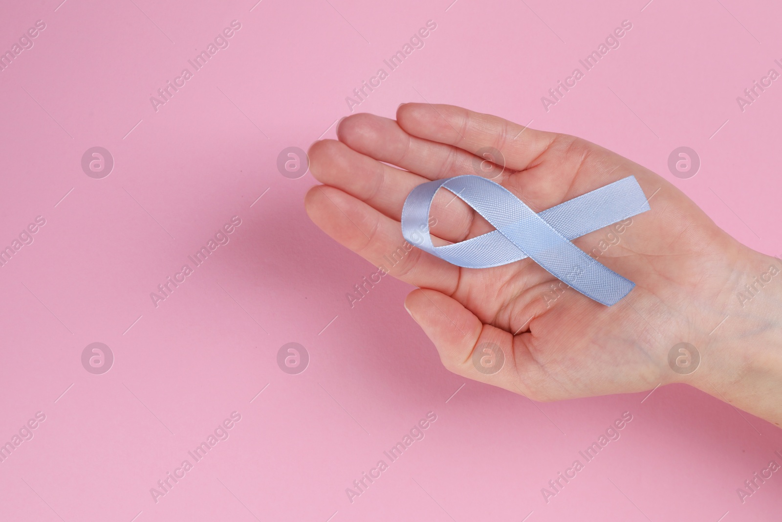 Photo of International Psoriasis Day. Woman with light blue ribbon as symbol of support on pink background, top view. Space for text