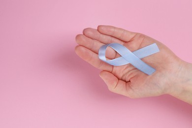 Photo of International Psoriasis Day. Woman with light blue ribbon as symbol of support on pink background, top view. Space for text