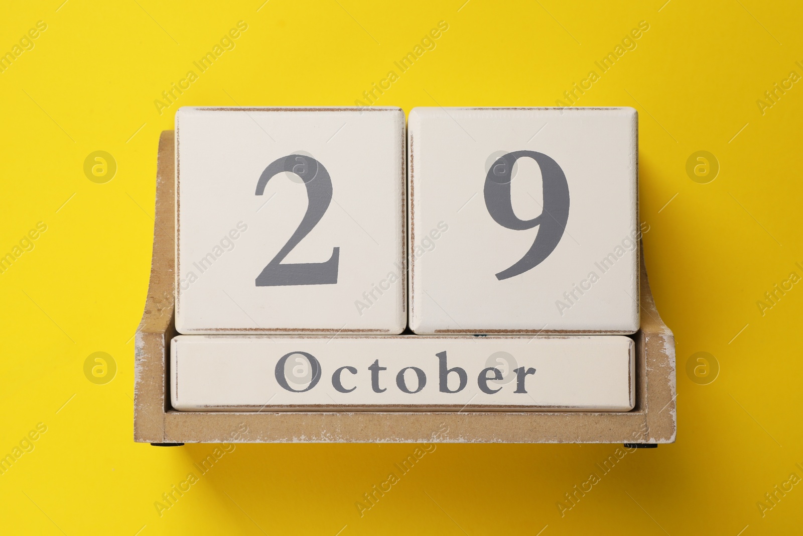 Photo of International Psoriasis Day - 29th of October. Block calendar on yellow background, top view