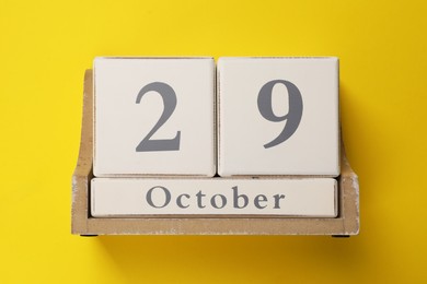 Photo of International Psoriasis Day - 29th of October. Block calendar on yellow background, top view