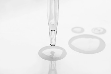 Photo of Glass pipette and transparent liquid on white background, closeup