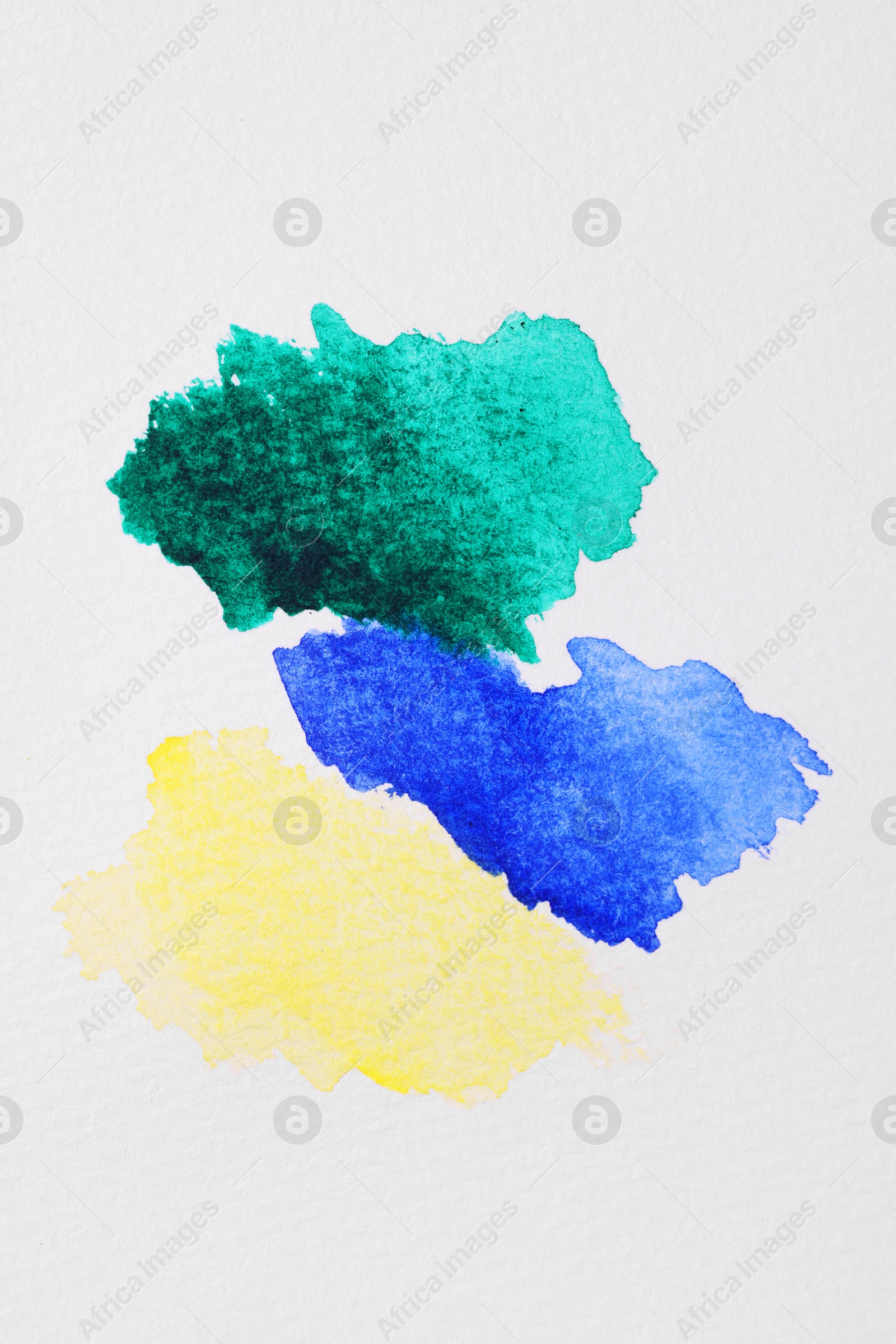 Photo of Blots of bright watercolor paints on white paper, top view