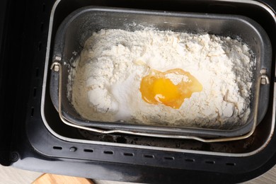 Photo of Making dough. Flour and egg in breadmaker pan, above view