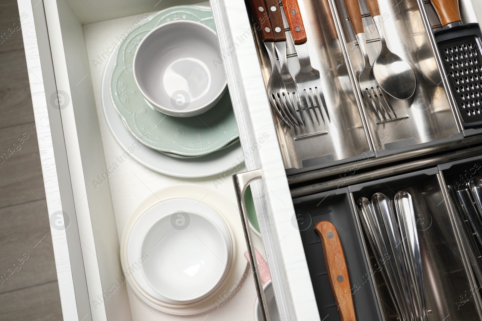 Photo of Ceramic dishware and cutlery in drawers indoors, above view