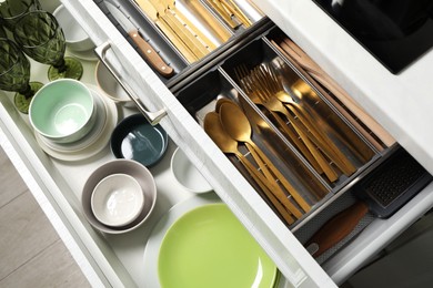 Photo of Ceramic dishware and cutlery in drawers indoors, above view