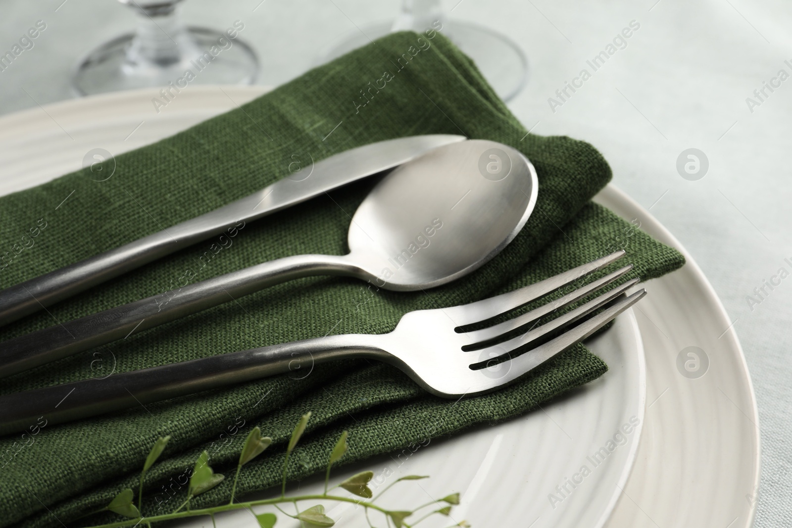 Photo of Stylish setting with cutlery, leaves and plates on table, closeup