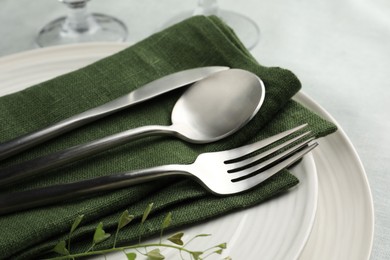 Stylish setting with cutlery, leaves and plates on table, closeup