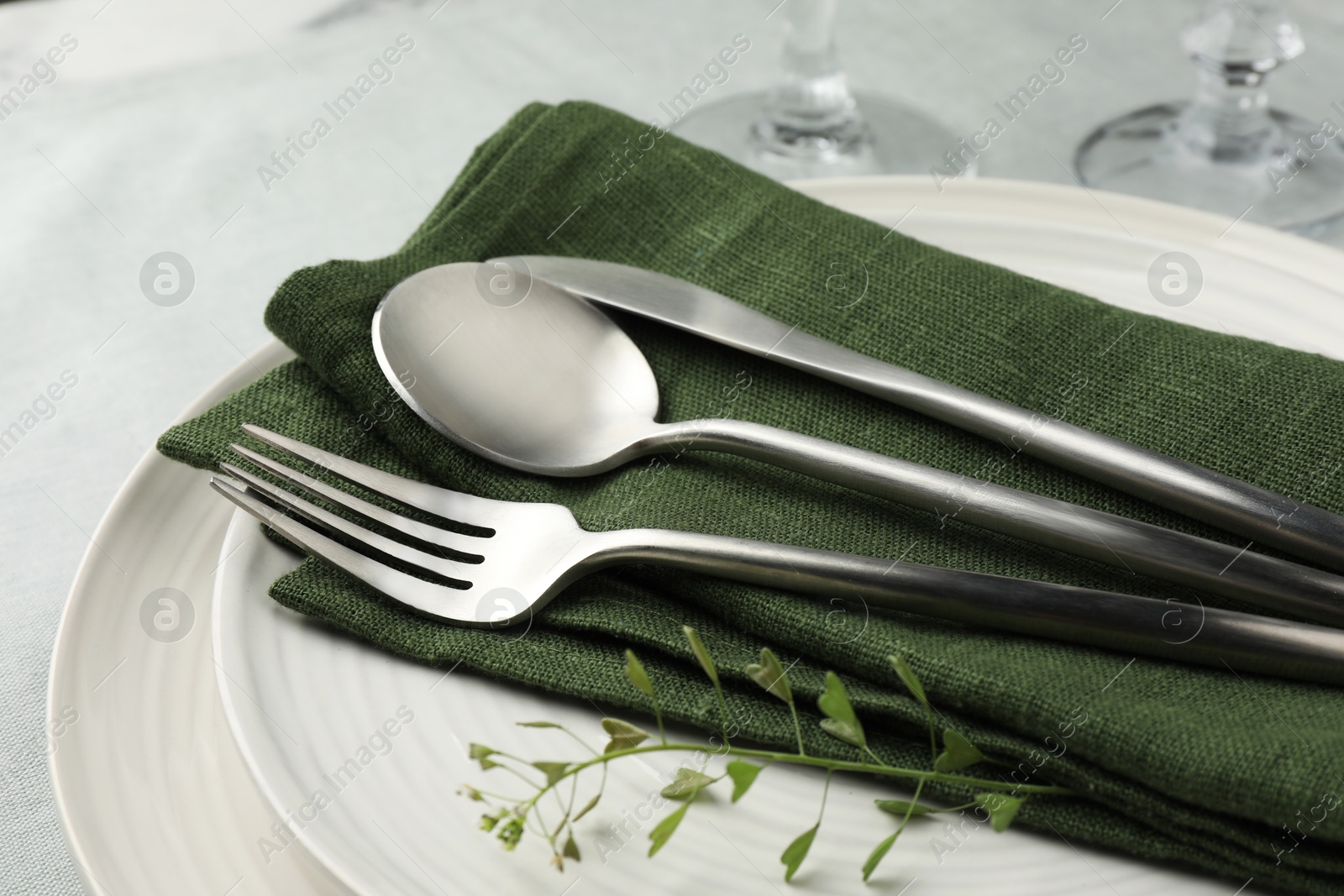 Photo of Stylish setting with cutlery, leaves and plates on table, closeup
