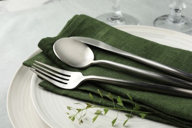 Stylish setting with cutlery, leaves and plates on table, closeup