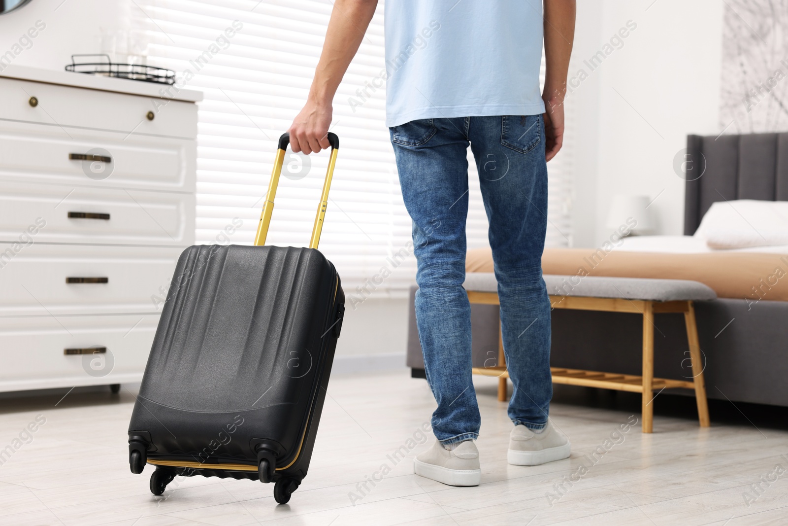 Photo of Guest with suitcase walking in hotel room, closeup