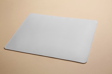 Photo of One mouse pad on beige background, closeup. Space for text